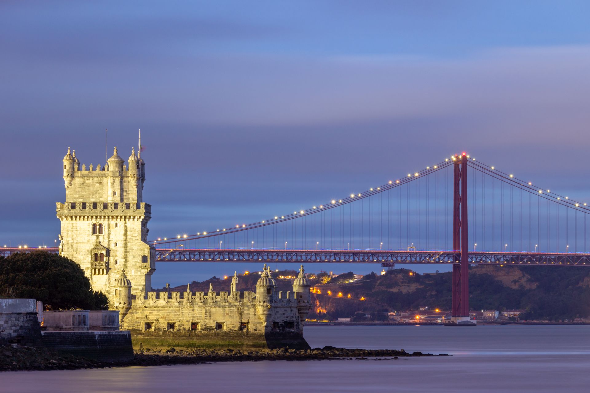 Belem Tower and 25th of April Bridge at Evening Twilight. Lisbon, Portugal