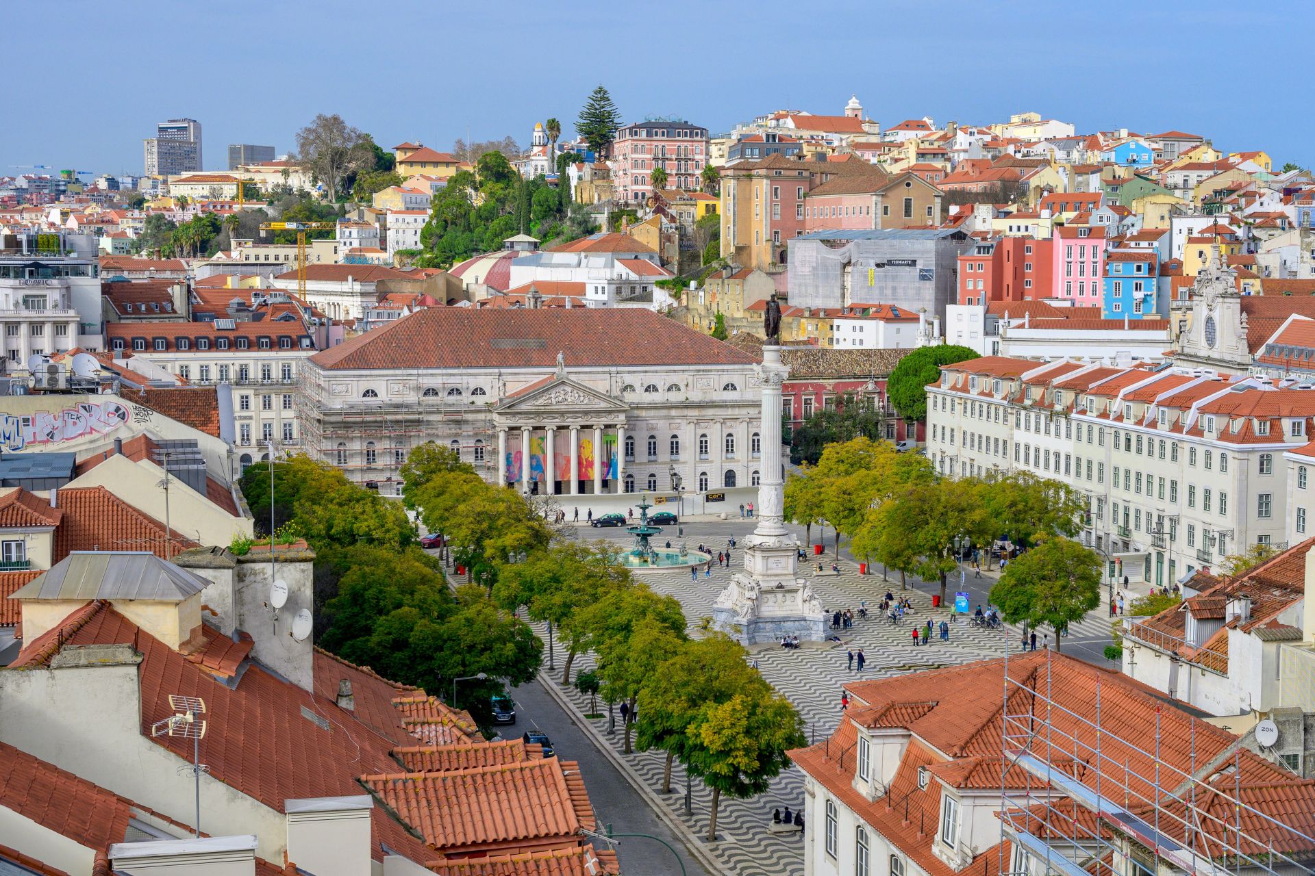 Beautiful view of Rossio Square in Lisbon, Portugal, with colorful buildings and a clear blue sky.
