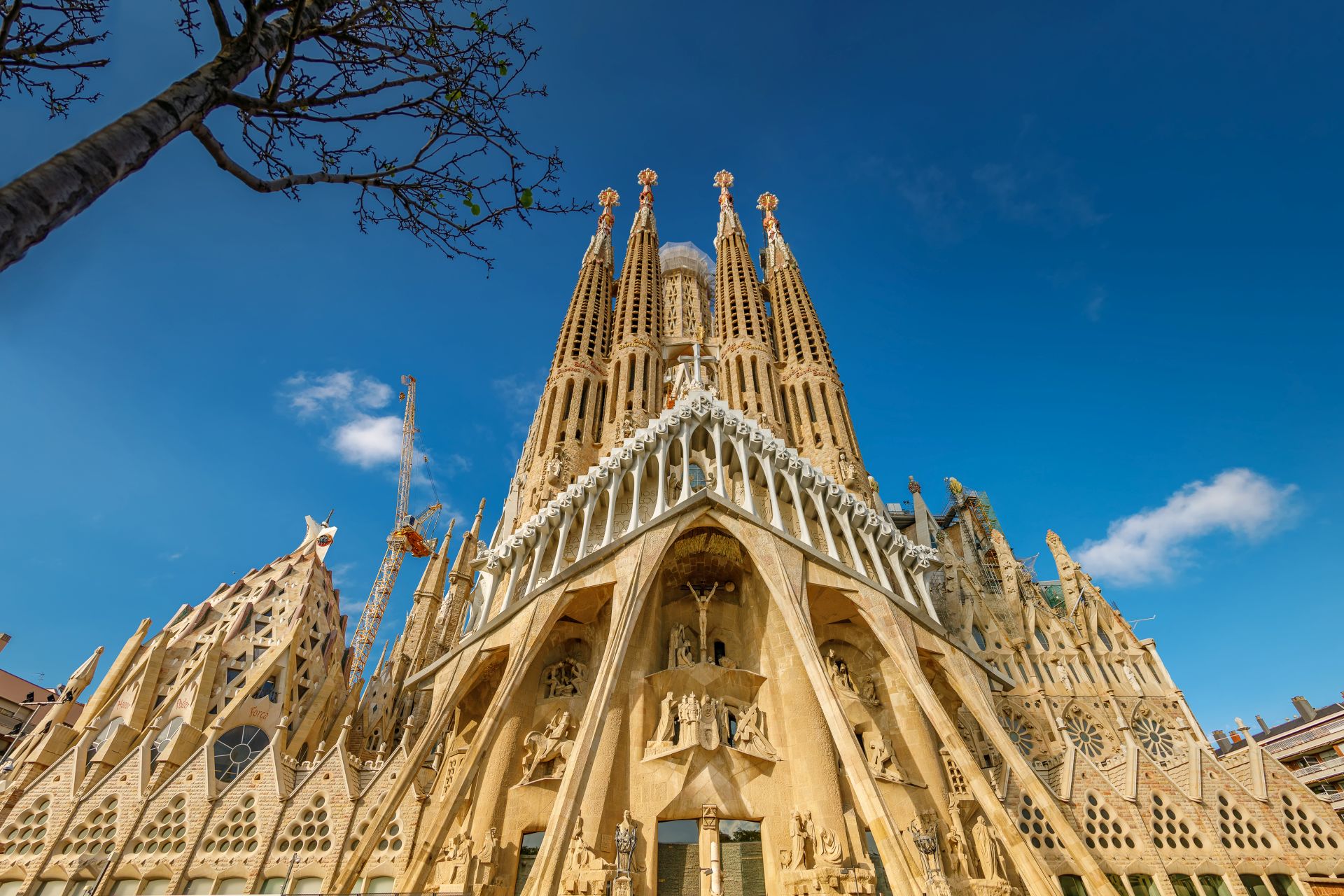 View of Sagrada Família basilica with spires, sculptures, and ornate carvings under clear sky in Barcelona